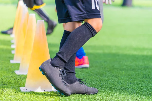 Children feet with soccer boots training on training cone on soc