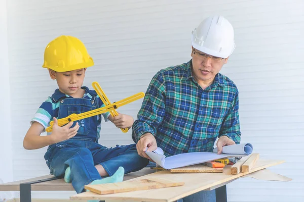 Батько - будівельник навчає сина читати план будівництва. — стокове фото