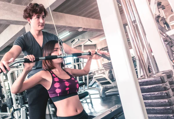 Mujer está trabajando en la máquina de fitness con entrenador masculino es hel — Foto de Stock