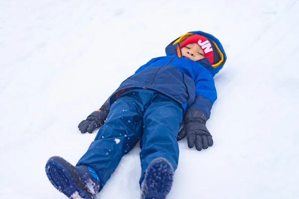 Little boy is lying down on snow — Stock Photo, Image