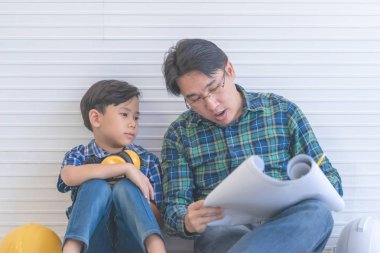 İnşaatçı baba oğluna inşaat planını okumayı öğretiyor.