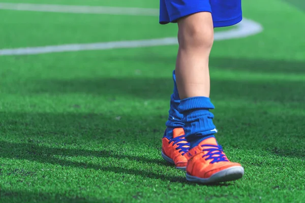 Niños pies con botas de fútbol entrenamiento en cono de entrenamiento en el césped — Foto de Stock
