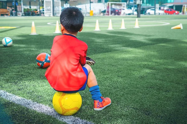 Mały chłopiec jest relaksujący w polu szkolenia piłki nożnej — Zdjęcie stockowe