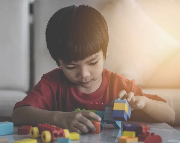 Азиатский мальчик укладывает игрушечные блоки на стол в гостиной — стоковое фото