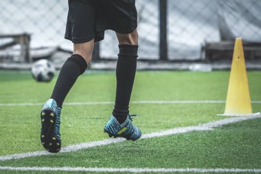 Çocuk ayakları futbol sahasında koşma ve hareket pratiği yapıyor.