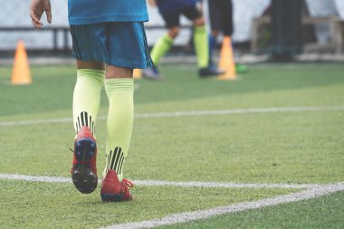 Çocuk ayakları futbol sahasında koşma ve hareket pratiği yapıyor.