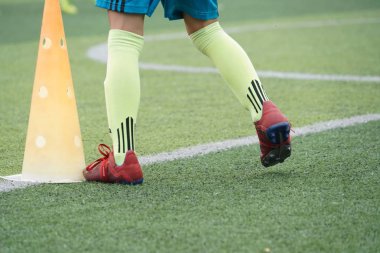 Çocuk ayakları futbol sahasında koşma ve hareket pratiği yapıyor.