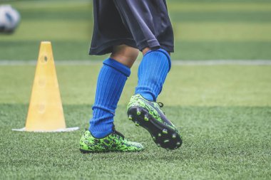 Çocuk ayakları futbol sahasında koşma ve hareket pratiği yapıyor.