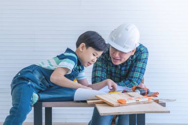 Mühendis baba oğluna inşaat kitabı okumayı öğretiyor.