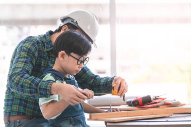 Küçük Çocuk ahşap üzerinde çalışmayı öğreniyor ve onun sayesinde inşaatçı oluyor.