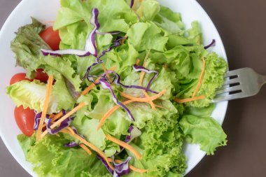 Beyaz yerde yeşil sebze salatası ve kahverengi masa.