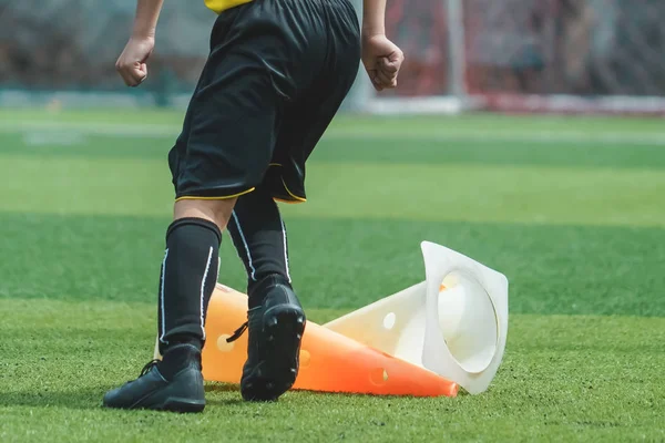 Niños pies está practicando saltar sobre el cono en el campo de fútbol — Foto de Stock