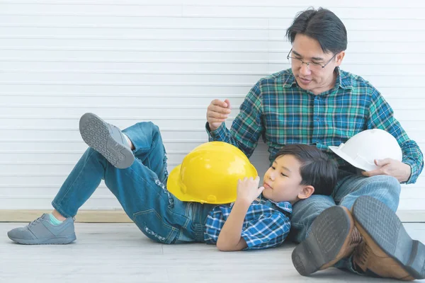 Маленький хлопчик-будівельник сидить на колінах Отця для перемикання дня батька — стокове фото