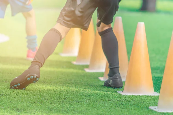Детские ножки в футбольных сапогах на тренировочном конусе на соке — стоковое фото