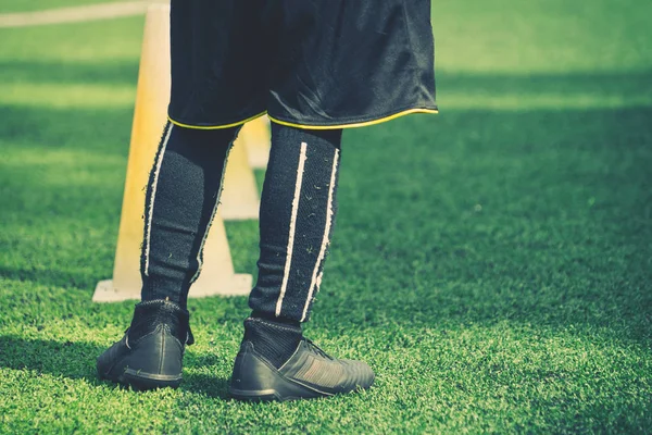 Niños pies con botas de fútbol entrenamiento en cono de entrenamiento en el césped — Foto de Stock