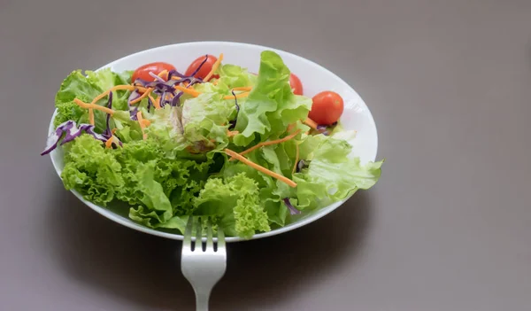 Grüner frischer Gemüsesalat auf weißem Platz und braunem Tisch — Stockfoto