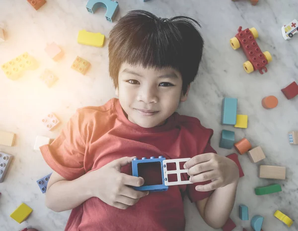 Mutlu çocuk açık kalp rüzgarlı renkli oyuncak bloklarıyla çevrili.