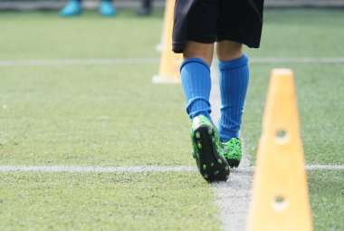 Çocuk ayakları futbol sahasında koşma ve hareket pratiği yapıyor.