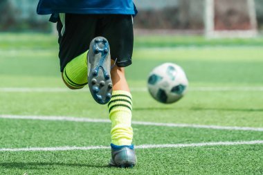 Çocuklar futbol antrenmanında top sürüp antrenman yapıyorlar.