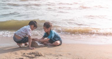 İki kardeş çocuk Pattaya B 'de kum ve el sallıyor.