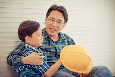 İnşaatçı baba aile bağlantısı için oğlunun yanında oturuyor. 