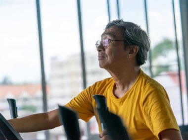 Son sınıf öğrencisi erkek, yaşlı sağlıklılar için fitness makinesinde çalışıyor. 