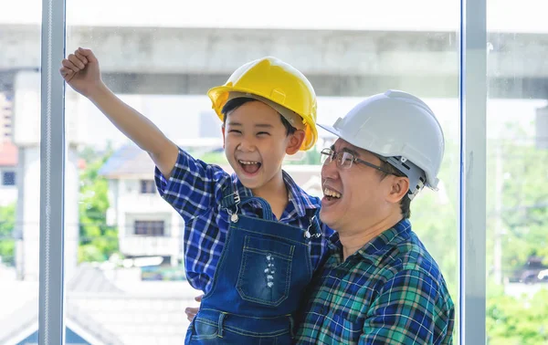Будівельник тримає свого сина в інженерному захисті. — стокове фото
