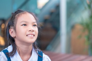 Mutlu Asyalı öğrenci dışarıda oturuyor.