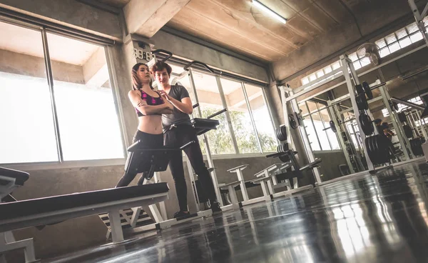 La mujer está trabajando en una máquina con entrenador masculino junto a él. — Foto de Stock