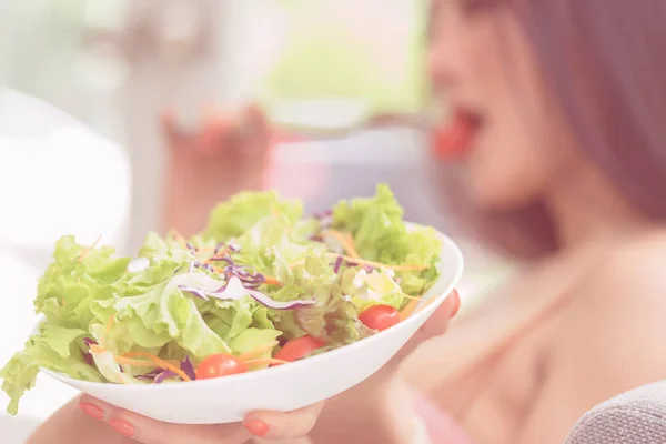 Mujer está comiendo verde saludable ensalada de verduras y relajarse en ho —  Fotos de Stock