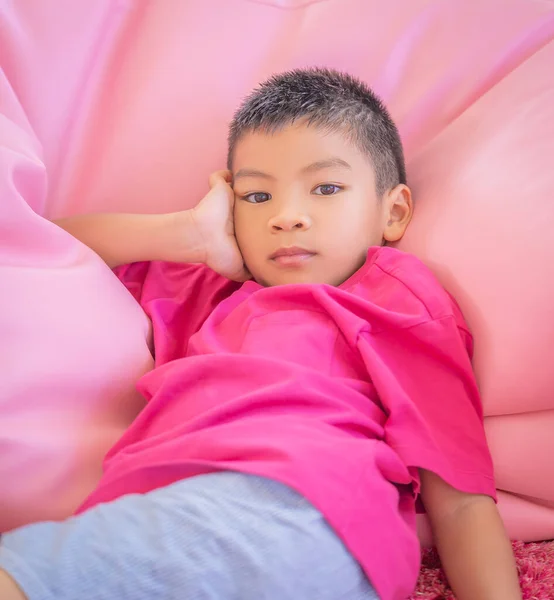 Asian Boy in pink shirt is resting on a pillow