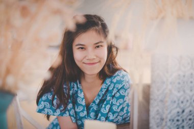 Güzel Asyalı Çinli bayan, ahşap kafede oturuyor..