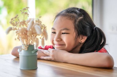 Çocuk kız, mutlu bir çocuk konsepti için kuru bir vazoya bakıp gülümsüyor..