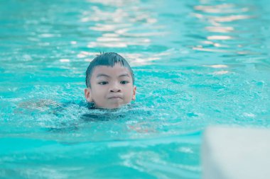 Çocuk yüzüyor ve suyun altına dalıyor.