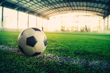 Futbol sahasında beyaz bir çizgi üzerinde duran tek bir futbol topu..