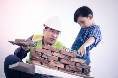 Küçük çocuk inşaatçı babasından eski usul tuğla yapmayı öğreniyor.