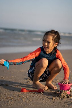 Küçük kız kumsalda dalga ve kumla oynuyor.