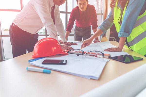 Construction team with business man engineer and architect is brainstorming on working table with building plan