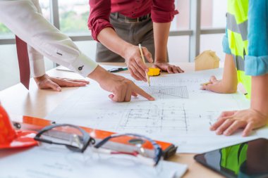 Construction team with business man engineer and architect is poiting on working table with building plan clipart