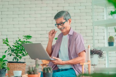 Üst düzey Asyalı, ev bahçesindeki aileyi aramak için dizüstü bilgisayar kullanıyor..