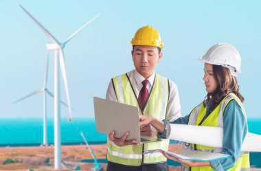 İki Sürdürülebilir Enerji mühendisi erkek ve dişi, Rüzgar türbiniyle belge fabrikasında tartışıyor.