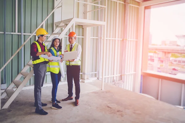 Üç inşaat müteahhiti, mühendis ve inşaat işçisi şantiyede inşaat planına itiraz ediyor..