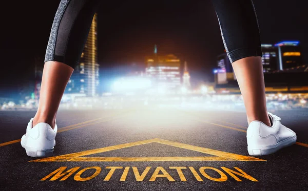 Woman runner leg standing on a motivation road sign leading to a Mdoern night city for motivation concept.