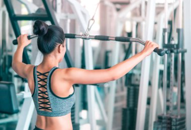 Asyalı kadın spor salonunda ağırlığını koyarak sırt kaslarını çalıştırıyor..