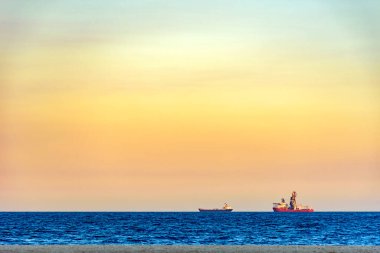 Rio de Janeiro 'daki Copacabana sahilinde tropikal günbatımında ufukta gemiler beliriyor.