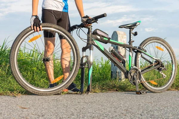 女子自行车自行车司机在前轮胎车轮的麻烦需要维修和调整自己的道路上 — 图库照片