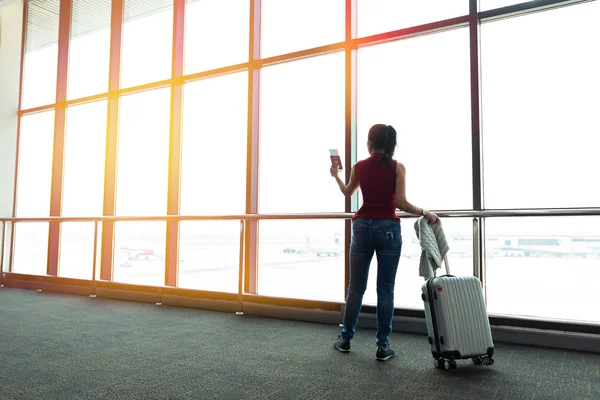 Jovem mulher está de pé perto da janela no aeroporto e assistindo — Fotografia de Stock