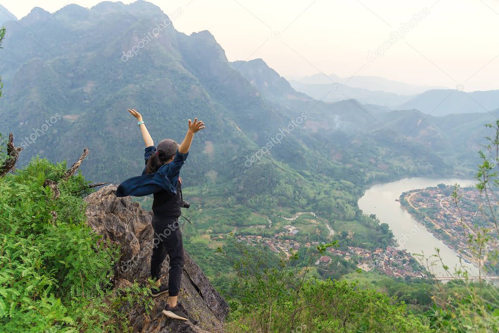 Woman hiker relaxing on a top of a mountain admiring surrounding