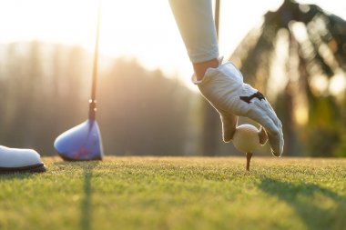 kadın golf oyuncusu nazik el ahşap tee üzerine bir golf topu koymak