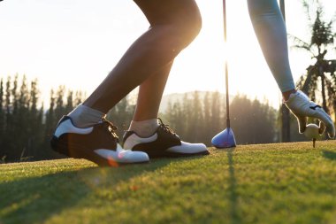 kadın golf oyuncusu nazik el ahşap tee üzerine bir golf topu koymak